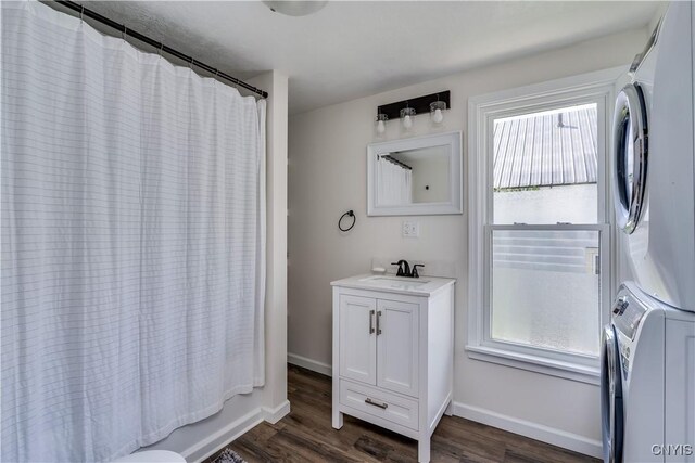 1010 Academy St, Watertown-City, NY 13601 - full bath featuring stacked washer / dryer, wood finished floors, vanity, and baseboards