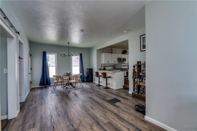 1010 Academy St, Watertown-City, NY 13601 - dining space featuring a chandelier, baseboards, dark wood-style flooring, and a textured ceiling