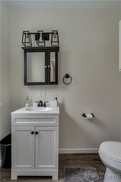 1010 Academy St, Watertown-City, NY 13601 - bathroom featuring vanity, toilet, baseboards, and wood finished floors