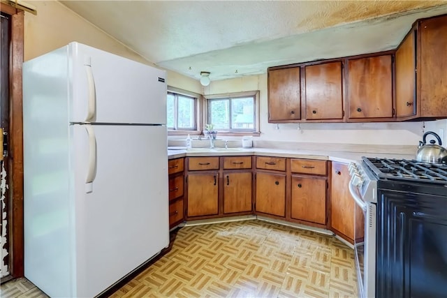 16 Welch Ave, Hamlin, NY 14470 - kitchen featuring freestanding refrigerator, stainless steel range with gas cooktop, brown cabinetry, light countertops, and a textured ceiling