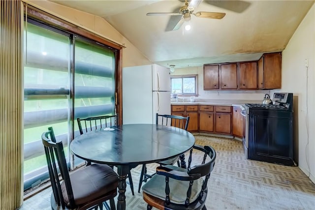 16 Welch Ave, Hamlin, NY 14470 - kitchen with stainless steel gas range, freestanding refrigerator, vaulted ceiling, brown cabinets, and ceiling fan