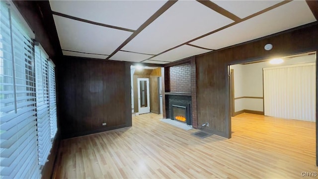 267 Fenway Dr, Syracuse, NY 13224 - unfurnished living room with wood walls, a fireplace, light wood finished floors, and baseboards