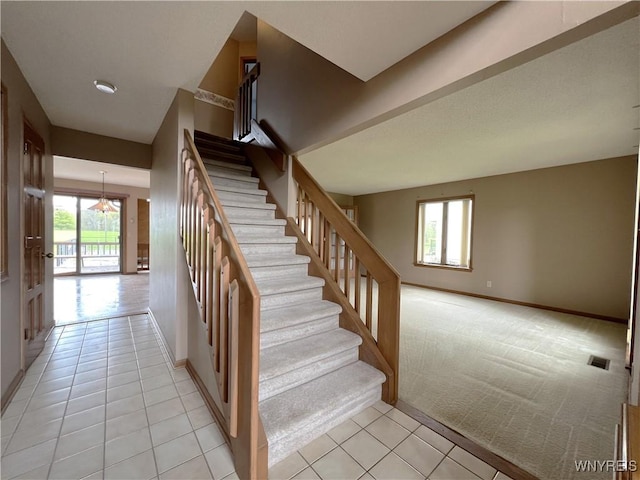 40 River Oaks Dr, Grand Island, NY 14072 - staircase with healthy amount of natural light, tile patterned floors, baseboards, and carpet flooring