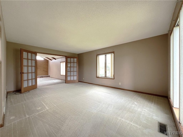 40 River Oaks Dr, Grand Island, NY 14072 - unfurnished room featuring light carpet, baseboards, a textured ceiling, and french doors