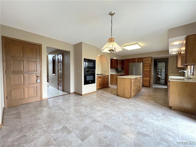 40 River Oaks Dr, Grand Island, NY 14072 - kitchen with black appliances, light countertops, brown cabinets, a center island, and baseboards