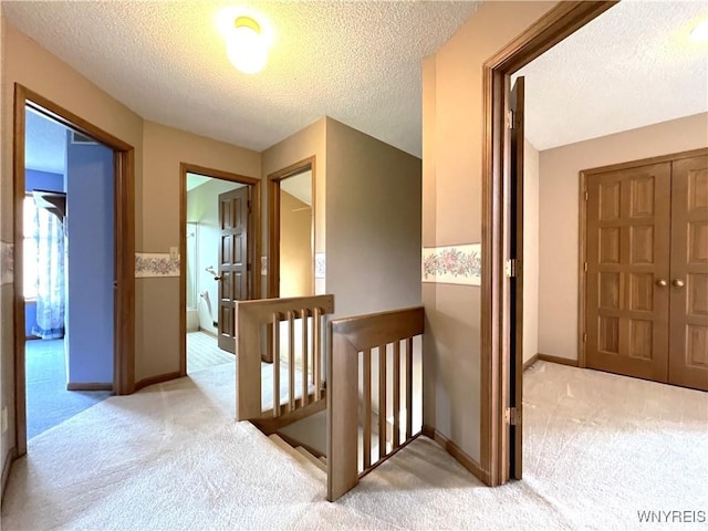 40 River Oaks Dr, Grand Island, NY 14072 - hall featuring an upstairs landing, light colored carpet, a textured ceiling, and baseboards