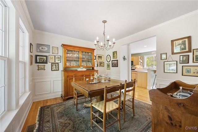 8105 Wilbarham Run, Pompey, NY 13104 - dining space with wood finished floors, a chandelier, crown molding, a decorative wall, and wainscoting
