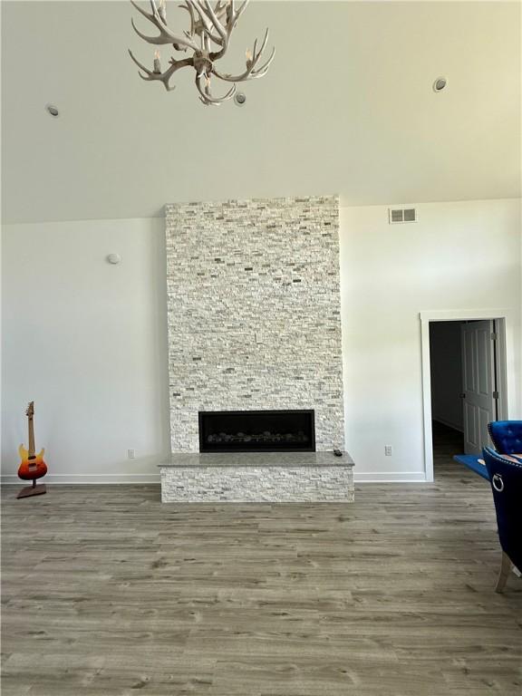 6731 County Road 12th Rd, South Bristol, NY 14512 - unfurnished living room featuring a chandelier, wood finished floors, a fireplace, baseboards, and a towering ceiling