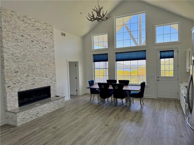 6731 County Road 12th Rd, South Bristol, NY 14512 - dining area with high vaulted ceiling, a chandelier, wood finished floors, baseboards, and a stone fireplace
