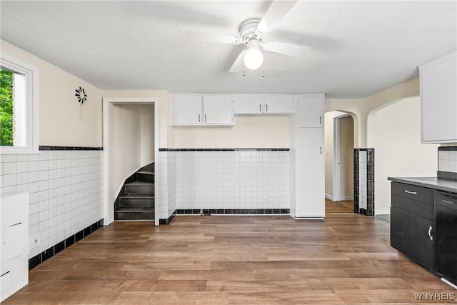 2365 Genesee St, Cheektowaga, NY 14225 - kitchen with tile walls, ceiling fan, light wood-style floors, white cabinets, and arched walkways