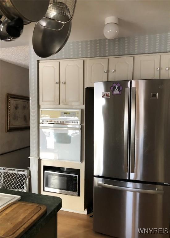 148 Marlin Rd, Grand Island, NY 14072 - kitchen featuring freestanding refrigerator, white double oven, white cabinetry, dark countertops, and wood finished floors