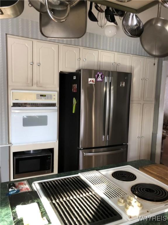 148 Marlin Rd, Grand Island, NY 14072 - kitchen featuring freestanding refrigerator, built in microwave, white cabinets, and white double oven