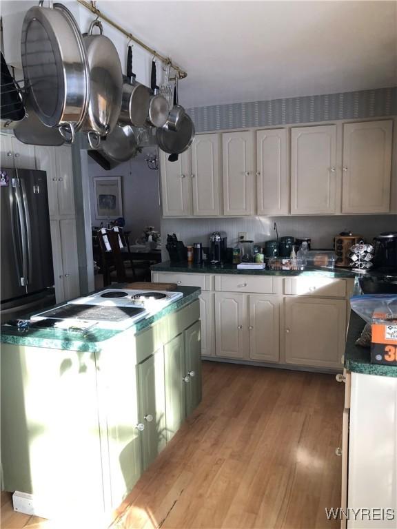 148 Marlin Rd, Grand Island, NY 14072 - kitchen featuring light wood-type flooring, dark countertops, a kitchen island, freestanding refrigerator, and white cabinets