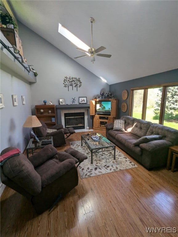 589 Briarwood Ln, Lewiston, NY 14092 - living room featuring ceiling fan, wood finished floors, a glass covered fireplace, a skylight, and high vaulted ceiling