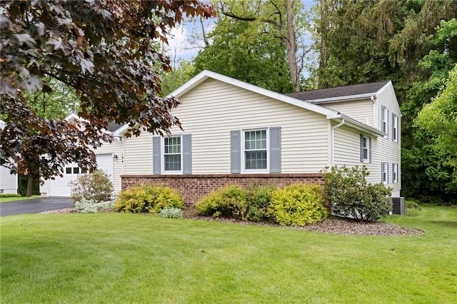 194 Citation Dr, Henrietta, NY 14467 - view of front of house with brick siding, asphalt driveway, a garage, a front lawn, and central AC