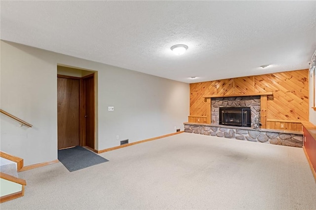 194 Citation Dr, Henrietta, NY 14467 - unfurnished living room with carpet floors, baseboards, a stone fireplace, wood walls, and stairway