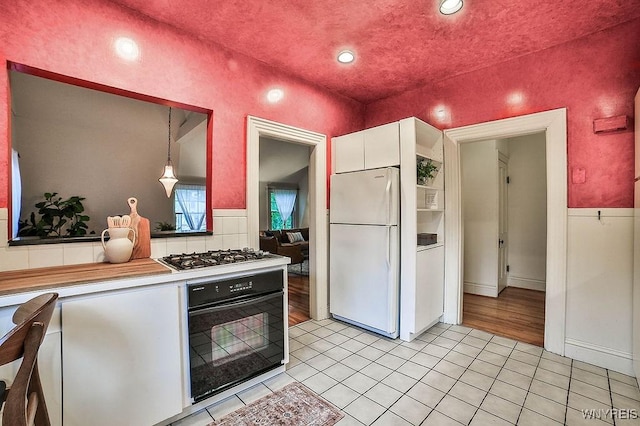 403 Elmwood Ave, Buffalo, NY 14222 - kitchen featuring freestanding refrigerator, oven, stainless steel gas cooktop, white cabinetry, and light tile patterned floors