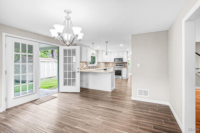 5 Glencrest Blvd, New Hartford, NY 13413 - kitchen with stainless steel appliances, a chandelier, tasteful backsplash, white cabinets, and a peninsula