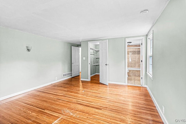 5 Glencrest Blvd, New Hartford, NY 13413 - unfurnished bedroom with light wood-style floors, baseboards, connected bathroom, and a spacious closet