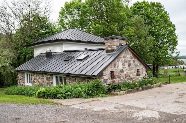 1466 Grant Rd, Russia, NY 13324 - view of front of house featuring a standing seam roof, stone siding, metal roof, and a chimney