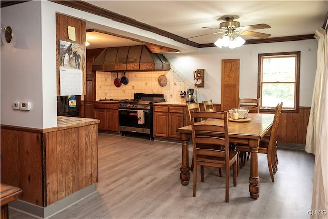 1466 Grant Rd, Russia, NY 13324 - dining area featuring wainscoting, light wood-type flooring, a ceiling fan, crown molding, and wood walls