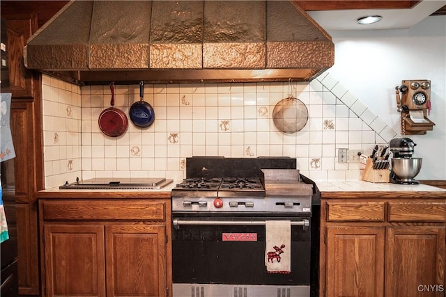 1466 Grant Rd, Russia, NY 13324 - kitchen with stainless steel gas stove, brown cabinetry, backsplash, and tile counters
