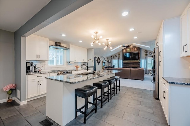25 San Mateo Rd, Chili, NY 14624 - kitchen featuring a sink, open floor plan, stone counters, wall chimney range hood, and a breakfast bar