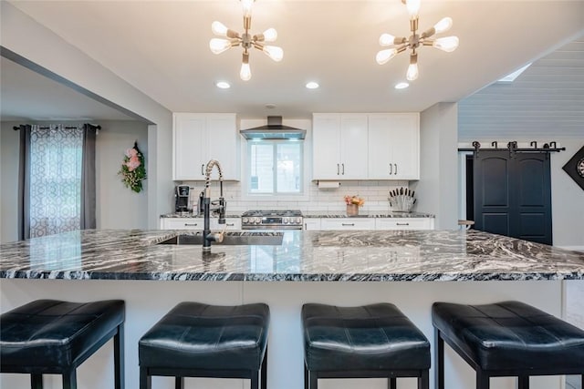 25 San Mateo Rd, Chili, NY 14624 - kitchen with stainless steel gas stove, wall chimney range hood, backsplash, a chandelier, and white cabinetry
