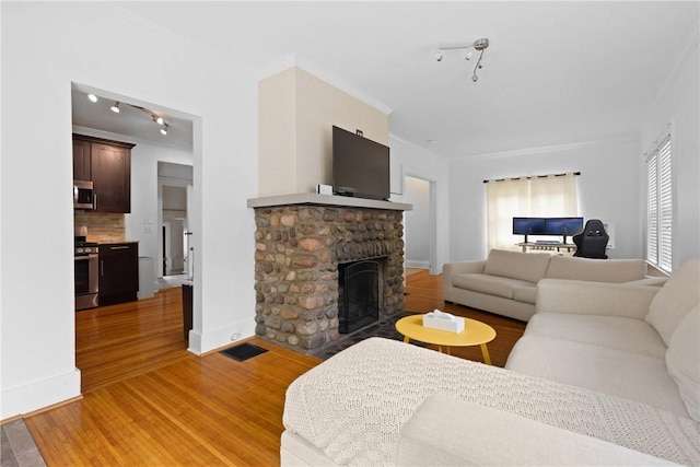 224 Lyell Ave, Ogden, NY 14559 - living room featuring a fireplace, track lighting, light wood-style floors, and baseboards