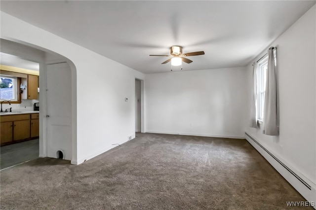 7514 Stephenson Ave, Niagara Falls, NY 14304 - carpeted empty room featuring a baseboard heating unit, a sink, ceiling fan, arched walkways, and baseboards