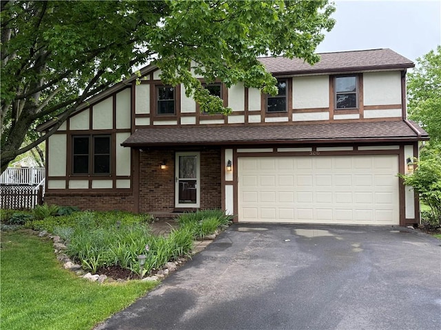 300 Amy Ln, Clarkson, NY 14420 - tudor home featuring asphalt driveway, stucco siding, a garage, and brick siding