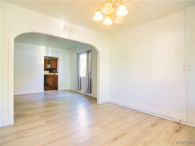 40 Federal Ave, Buffalo, NY 14215 - empty room featuring arched walkways, a chandelier, light wood finished floors, crown molding, and baseboards