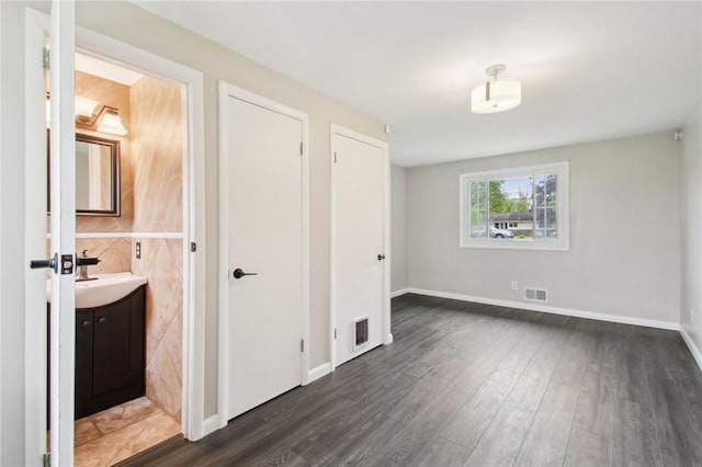 1099 N Greece Rd, Greece, NY 14626 - unfurnished bedroom featuring a sink, dark wood finished floors, ensuite bath, and baseboards