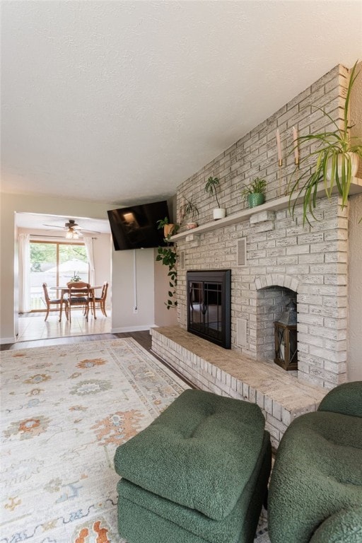 25 Selkirk Dr, Greece, NY 14626 - living area featuring a brick fireplace, baseboards, a textured ceiling, and a ceiling fan