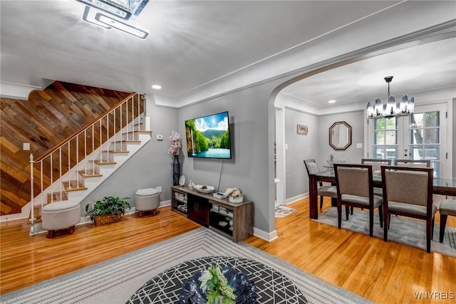 1597 Kensington Ave, Cheektowaga, NY 14215 - living area featuring wood finished floors, arched walkways, a chandelier, stairs, and baseboards