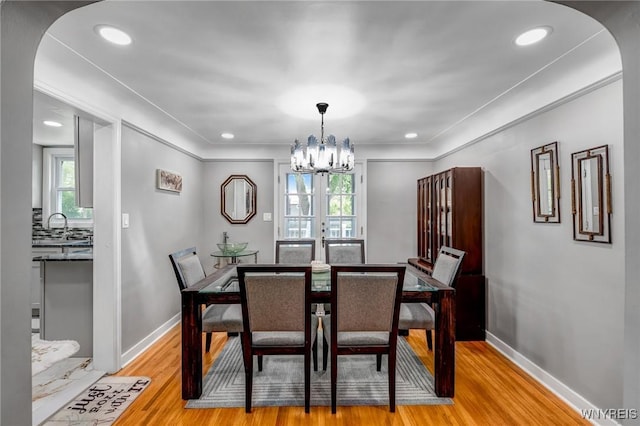 1597 Kensington Ave, Cheektowaga, NY 14215 - dining space featuring light wood-type flooring, arched walkways, a chandelier, baseboards, and ornamental molding
