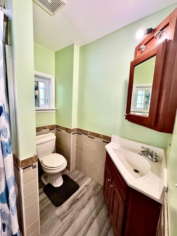 450 Stover Rd, Tyrone, NY 14815 - full bath featuring tile walls, wood finished floors, a wainscoted wall, toilet, and vanity