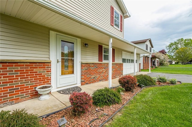 63 Shadywood Dr, Gates, NY 14606 - property entrance featuring brick siding, asphalt driveway, a lawn, a porch, and an attached garage