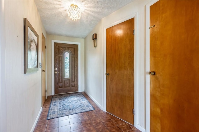 63 Shadywood Dr, Gates, NY 14606 - foyer entrance with dark tile patterned floors, a chandelier, a textured ceiling, and baseboards