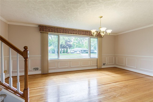 63 Shadywood Dr, Gates, NY 14606 - unfurnished room featuring a chandelier, a textured ceiling, light wood-type flooring, a decorative wall, and stairway