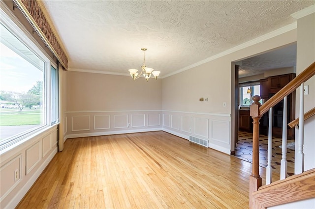 63 Shadywood Dr, Gates, NY 14606 - unfurnished room with light wood-style floors, a chandelier, a wainscoted wall, ornamental molding, and a decorative wall