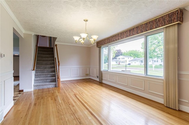 63 Shadywood Dr, Gates, NY 14606 - spare room featuring light wood-type flooring, a decorative wall, ornamental molding, stairs, and a chandelier