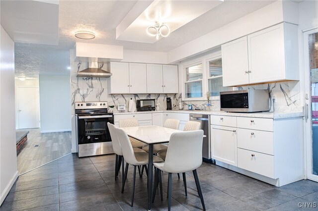 4335 US Route 11, Richland, NY 13142 - kitchen with appliances with stainless steel finishes, wall chimney range hood, decorative backsplash, and white cabinetry