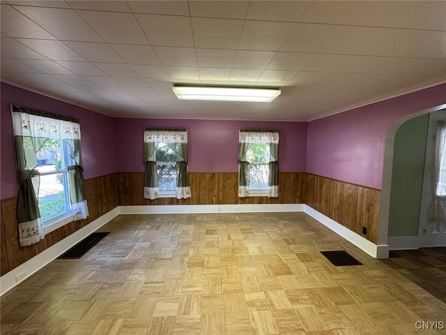 109 Clinton Ave, Cortland, NY 13045 - spare room featuring a wainscoted wall, wooden walls, arched walkways, baseboards, and crown molding