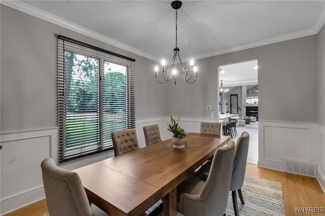 110 Hunt Club Cir, Amherst, NY 14051 - dining room with a chandelier, crown molding, a decorative wall, light wood-style floors, and a wainscoted wall