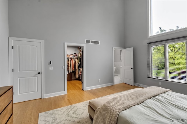 110 Hunt Club Cir, Amherst, NY 14051 - bedroom with a towering ceiling, a walk in closet, baseboards, light wood-type flooring, and connected bathroom