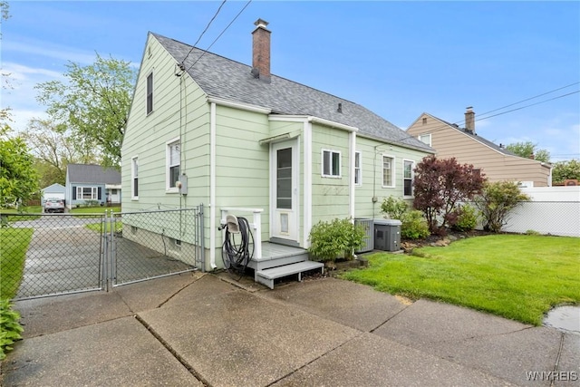 234 Clark St, Tonawanda-Town, NY 14223 - back of house with a gate, a chimney, roof with shingles, and central AC unit