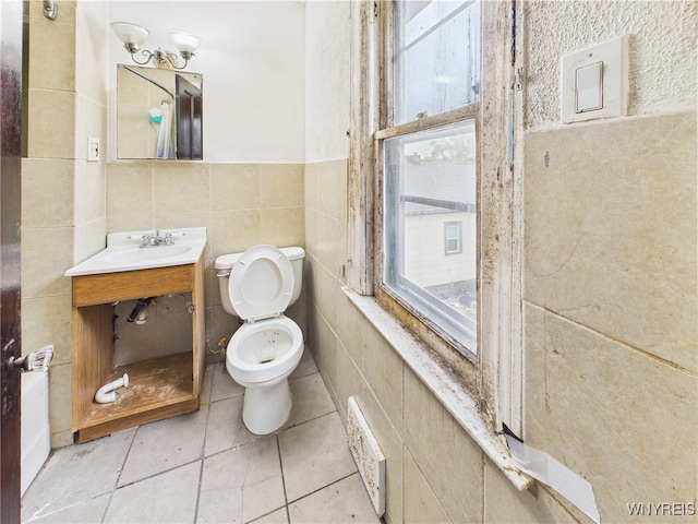 1307 Michigan Ave, Niagara Falls, NY 14305 - half bath with tile walls, toilet, vanity, tile patterned flooring, and a wainscoted wall