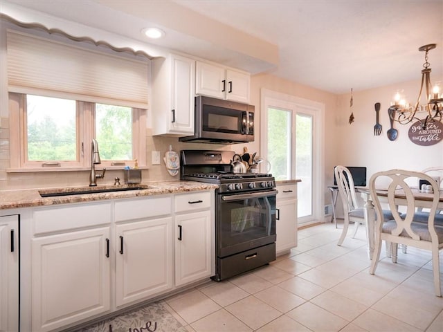 39 Sahara Dr, Gates, NY 14624 - kitchen with black gas range, stainless steel microwave, a sink, a chandelier, and white cabinets