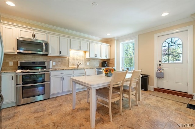 8785 Main St, Clarence, NY 14221 - kitchen with appliances with stainless steel finishes, ornamental molding, tasteful backsplash, white cabinets, and recessed lighting